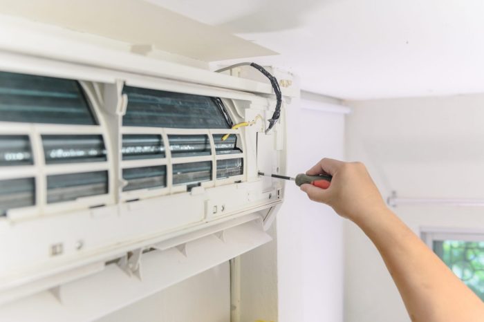 Photo of person using a screwdriver on AC unit illustrates blog "This Is Why You Shouldn’t Repair Your AC Yourself"