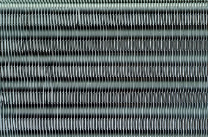 Photo of coil fins illustrates blog: "Why Is It Important to Fix Bent Coil Fins? Bent condenser coil fins may seem like small potatoes compared to other AC problems. However, while it’s true that this is a relatively simple task, that doesn’t mean that you should overlook it. Keep reading to learn more. Why Is It Important to Fix Bent Coil Fins? As you may have noticed, it’s not uncommon for the fins on your condenser coil to get bent over time. This is more than a cosmetic issue, as bent fins can impact the performance of your HVAC unit. Coil fins are really thin, so they can bend at the slightest contact, like hail, sleet, or pressure washing for example. Needless to say, you can also bend your coil fins while cleaning your coils or changing a filter. Coil fins play an important role in the heat transfer process that keeps your home cool. Bent coil fins increase heat retention, hindering the efficiency of your unit How To Fix Bent Condenser Coil Fins Straightening bent condenser coil fins is relatively easy but you should consider doing it yourself only if you feel 100% confident performing the tasks outlined below. If you don’t feel comfortable carrying out these steps, or just don’t have the time, don’t worry — you can always contact our experts at Zero Heating AC and Refrigeration, and they’ll take care of it. The first thing to do is to have the right tool, so make sure to purchase a coil fin comb. They usually come with several interchangeable heads, so you don’t have to worry about buying a specific type of comb. Turn off the power to your air conditioner Remove the panel and grille to expose the fins Remove screws and lift off the fan and grille Take off the plate to the evaporator coil Use the appropriate fin comb head and start straightening from the bottom I Zero Heating AC and Refrigeration: the Best In San Antonio, TX Whether you need to repair or replace your AC unit, Zero Heating AC and refrigeration and Refrigeration is your best option in San Antonio, Texas. Contact us today using our website, by telephone (210-900-0824), or through our social media accounts on Facebook and Twitter and to schedule a tune-up or to get a free estimate. We also offer financing plans for your convenience."