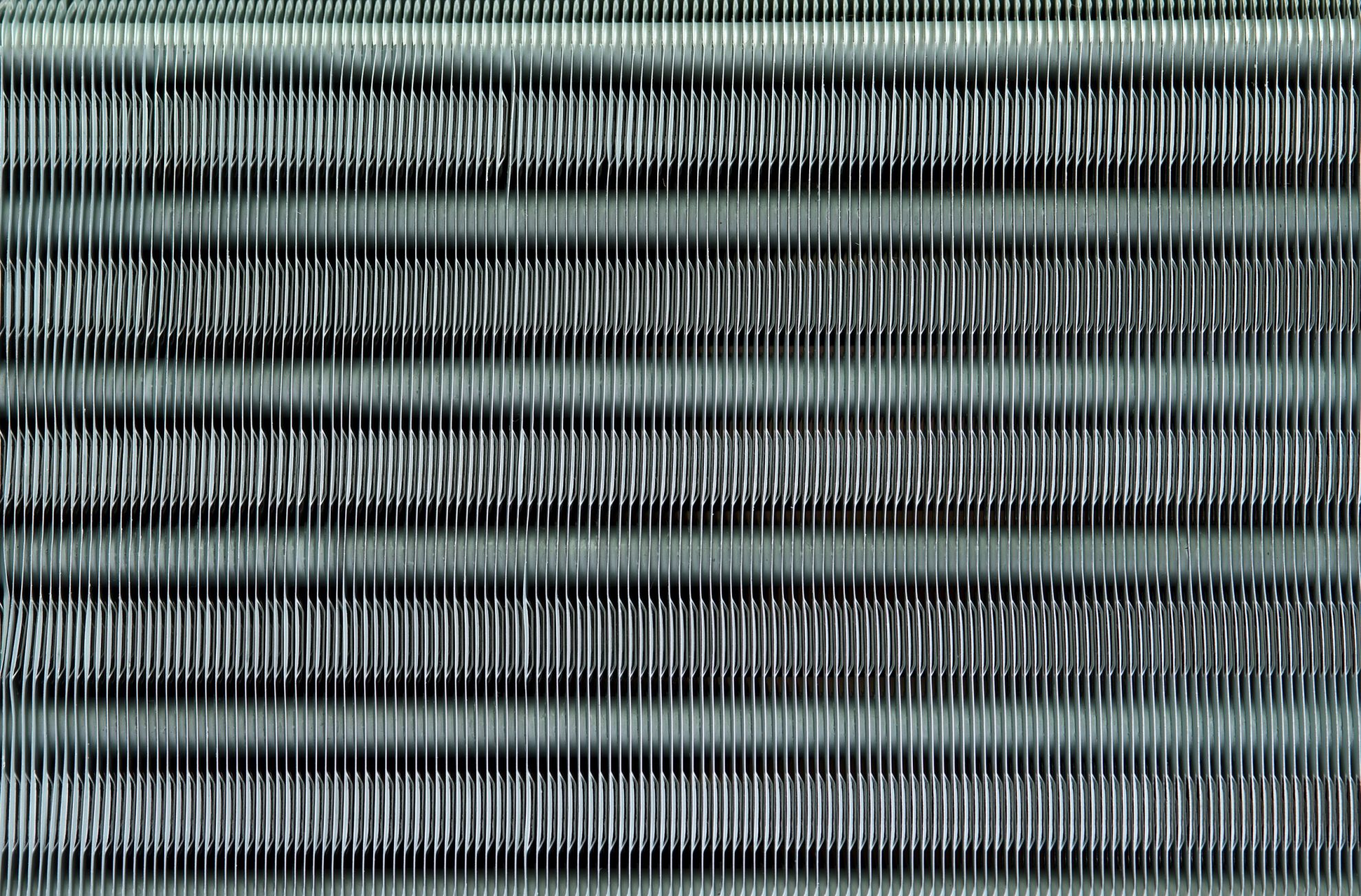 Photo of coil fins illustrates blog: "Why Is It Important to Fix Bent Coil Fins? Bent condenser coil fins may seem like small potatoes compared to other AC problems. However, while it’s true that this is a relatively simple task, that doesn’t mean that you should overlook it. Keep reading to learn more. Why Is It Important to Fix Bent Coil Fins? As you may have noticed, it’s not uncommon for the fins on your condenser coil to get bent over time. This is more than a cosmetic issue, as bent fins can impact the performance of your HVAC unit. Coil fins are really thin, so they can bend at the slightest contact, like hail, sleet, or pressure washing for example. Needless to say, you can also bend your coil fins while cleaning your coils or changing a filter. Coil fins play an important role in the heat transfer process that keeps your home cool. Bent coil fins increase heat retention, hindering the efficiency of your unit How To Fix Bent Condenser Coil Fins Straightening bent condenser coil fins is relatively easy but you should consider doing it yourself only if you feel 100% confident performing the tasks outlined below. If you don’t feel comfortable carrying out these steps, or just don’t have the time, don’t worry — you can always contact our experts at Zero Heating AC and Refrigeration, and they’ll take care of it. The first thing to do is to have the right tool, so make sure to purchase a coil fin comb. They usually come with several interchangeable heads, so you don’t have to worry about buying a specific type of comb. Turn off the power to your air conditioner Remove the panel and grille to expose the fins Remove screws and lift off the fan and grille Take off the plate to the evaporator coil Use the appropriate fin comb head and start straightening from the bottom I Zero Heating AC and Refrigeration: the Best In San Antonio, TX Whether you need to repair or replace your AC unit, Zero Heating AC and refrigeration and Refrigeration is your best option in San Antonio, Texas. Contact us today using our website, by telephone (210-900-0824), or through our social media accounts on Facebook and Twitter and to schedule a tune-up or to get a free estimate. We also offer financing plans for your convenience."