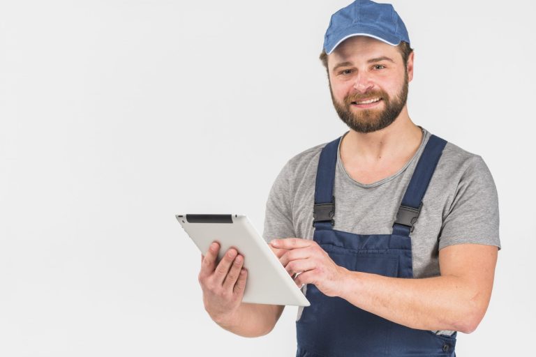 Handyman holding tablet illustrates blog "Why Is My AC Fan Spinning Backwards?"