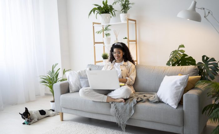 woman-living-room-fp Woman sitting in living room with laptop illustrates blog "What Are the Most Common AC Condenser Unit Issues?"